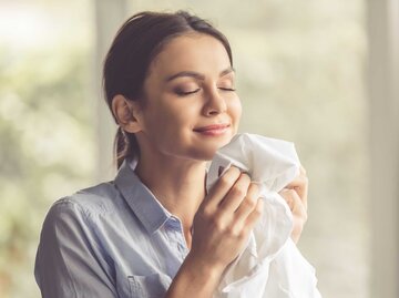 Frau steht im Raum und rieht an frischer weißer Wäsche. | © Adobe Stock/VadimGuzhva