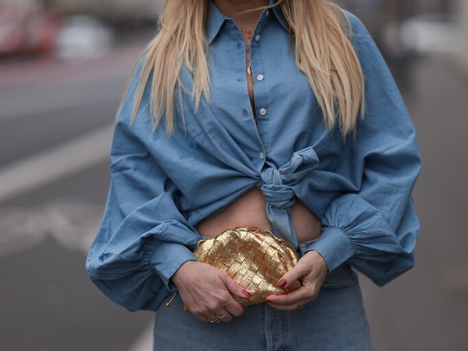 Streetstyle von Frau mit langen, blonden Haaren, die geknotete Jeansbluse trägt | © Getty Images/Jeremy Moeller