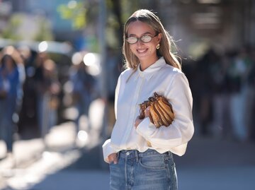 Streetstyle von Isabelle Allain mit weißer Bluse, blauen Jeans und Brille | © Getty Images/Jeremy Moeller