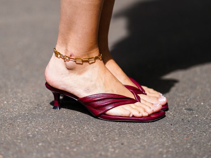 Streetstyle von Füßen in weinroten Flip-Flops | © Getty Images/Edward Berthelot