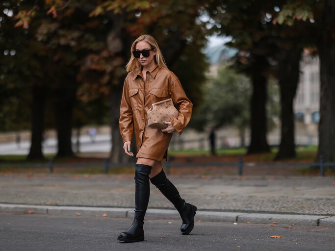 Streetstyle von Sonia Lyson in braunem Lederkleid und schwarzen Overknee-Stiefeln | © Getty Images/Jeremy Moeller