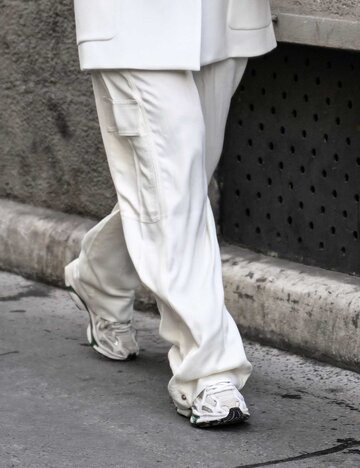 Frau trägt weißen Hosenanzug und helle Sneaker. | © Getty Images/Daniel Zuchnik