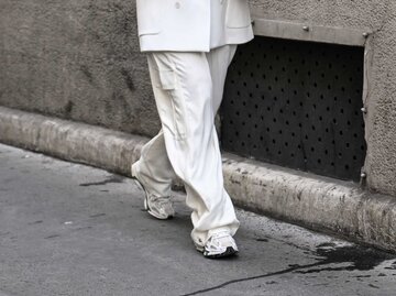 Frau trägt weißen Hosenanzug und helle Sneaker. | © Getty Images/Daniel Zuchnik