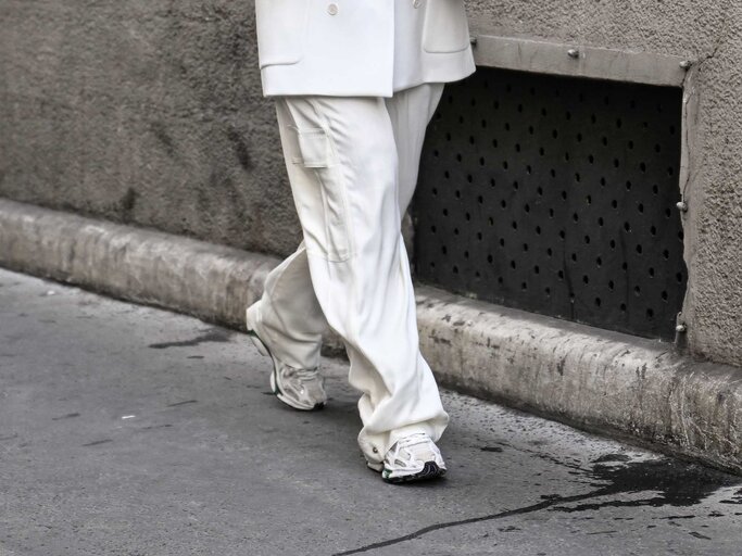 Frau trägt weißen Hosenanzug und helle Sneaker. | © Getty Images/Daniel Zuchnik