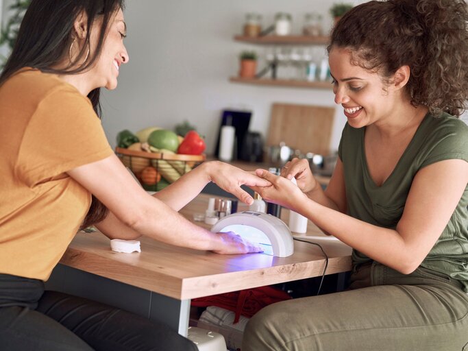 Zwei Freundinnen machen sich gegenseitig Gelnägel | © Getty Images / gpointstudio