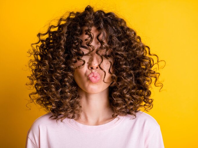 Porträt einer Frau mit langen braunen Locken | © Getty Images / Deagreez