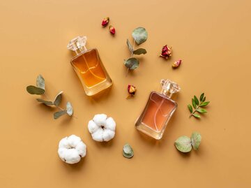 Parfum-Flakons und Blütenblätter vor einem gelben Hintergrund | © Adobe Stock/9dreamstudio