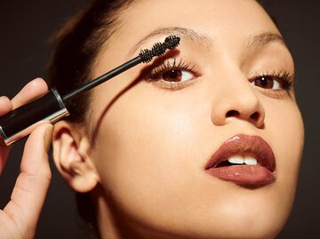 Eine junge Frau trägt sich Tubing Mascara auf. | © GettyImages/Plume Creative