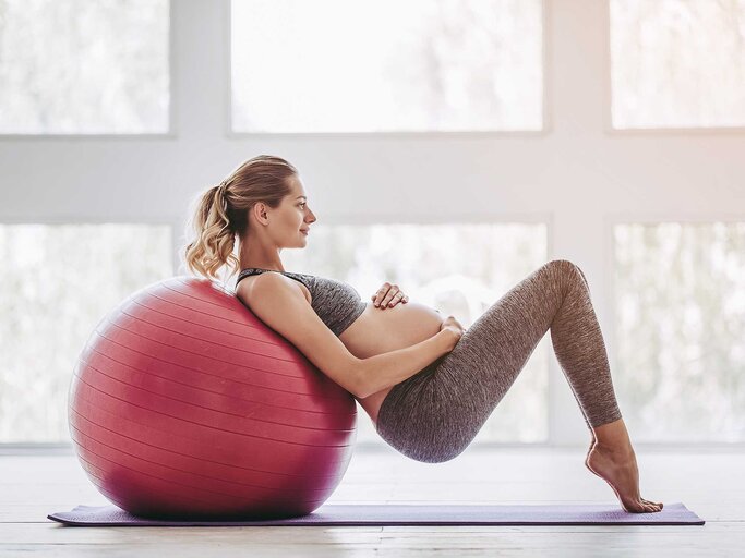 Schwangere Frau trainiert mit dem Schwebesitz auf einem Gymnastikball. | © Getty Images / Vasyl Dolmatov