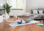 Frau macht Fitnessübung im Wohnzimmer | © Getty Images/Robert Niedring