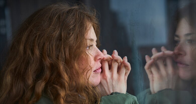 Eine junge Frau kann ihr Gedankenkarussell nicht stoppen und starrt aus dem Fenster. | © GettyImages/Justin Case