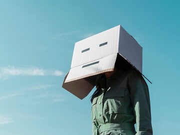 Frau mit Karton über dem Kopf vor blauem Himmel | ©  gettyimages.de | Westend61