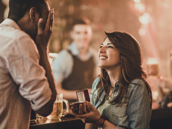 Frau macht ihrem Freund in einer Bar einen Heiratsantrag | © gettyimages.de | skynesher