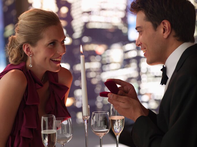 Mann im Anzug macht seiner Freundin einen Antrag beim Candlelightdinner | © gettyimages.de | Chris Ryan