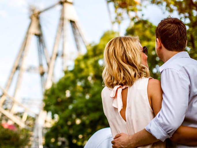 Pärchen von hinten fotografiert, geht auf eine Riesenrad zu. | © gettyimages.de | AleksandarNakic