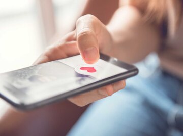 Eine Frau tippt in einer App auf ein Herzsymbol und wird Opfer von Catfishing | © Adobe Stock/oatawa