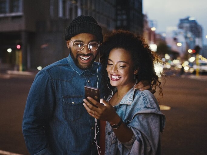 Pärchen mit Smartphone in stimmungsvoller Umgebung | © gettyimages.de | Delmaine Donson