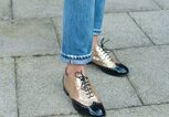 Detailaufnahme des Streetstyles der Influencerin Soraya Bakhtiar in gold-schwarzen Brogues von Chanel und Straight Leg-Jeans bei der Fashion Week in London | © Getty Images / Kirstin Sinclair