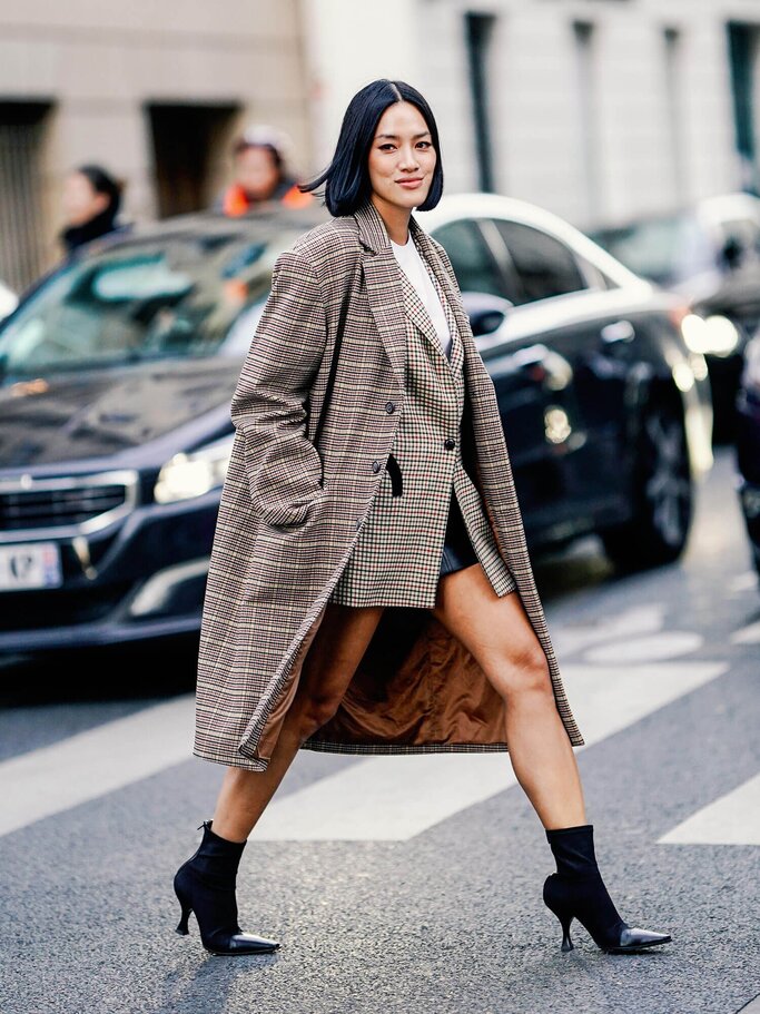 Tiffany Hsu wears a checked coat, a checked blazer jacket, a white top, black boots | © Getty Images | Edward Berthelot 