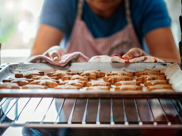 Mann holt Blech mit Plätzchen aus dem Ofen | © iStock | GMVozd