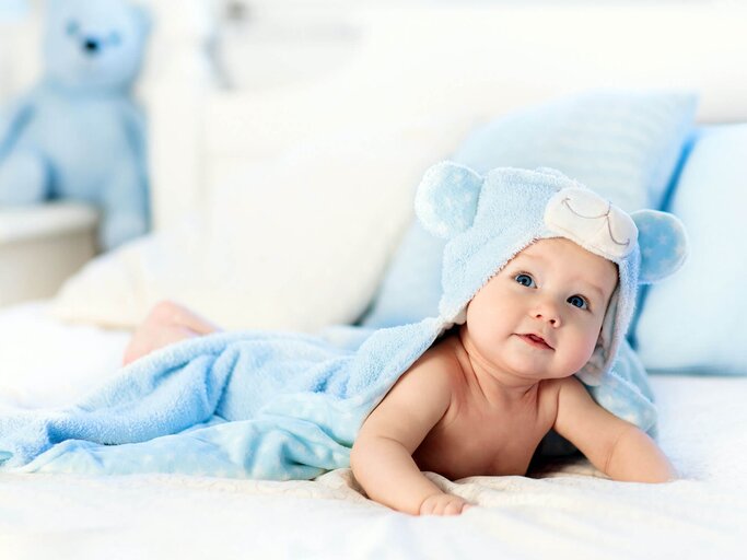 Baby Junge in Blau Handtuch auf weiß-Bett | © iStock | FamVeld