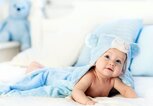 Baby Junge in Blau Handtuch auf weiß-Bett | © iStock | FamVeld