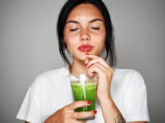 Frau schlürft einen grünen Smoothie | © iStock | FGorgun