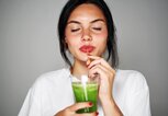 Frau schlürft einen grünen Smoothie | © iStock | FGorgun