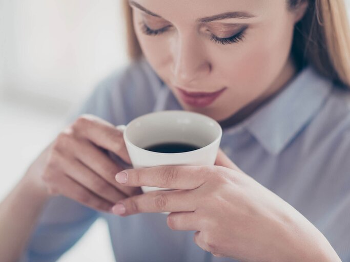 Frau trinkt Kaffee aus einer Tasse | © iStock | Deagreez