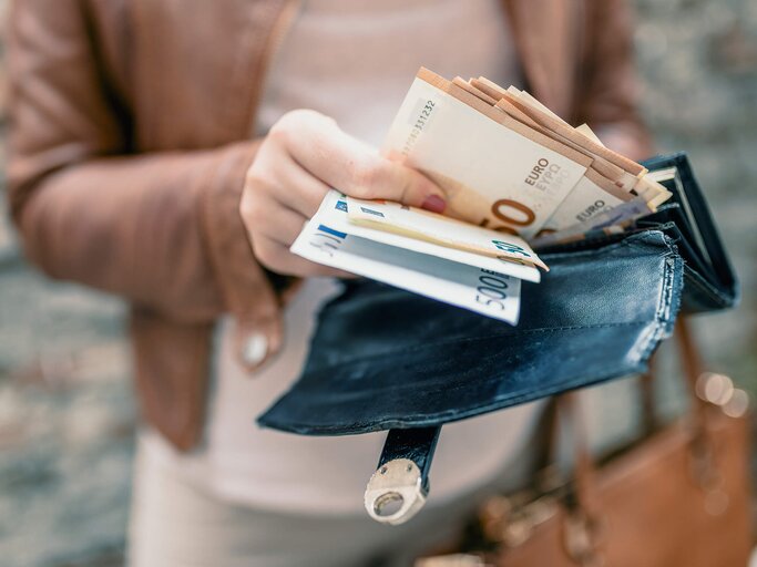Frau hält eine Brieftasche mit Bargeld in der Hand | © iStock | dragana991