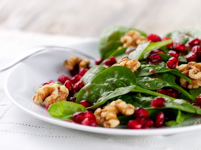 Teller mit einem Spinat-Salat mit Granatapfelkernen und Walnüssen | © iStock | nicolesy