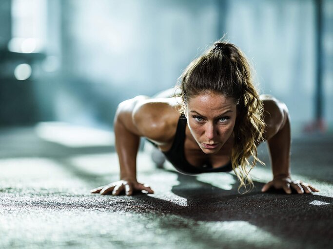 Frau macht Push-Ups im Fitnessclub | © iStock | skynesher