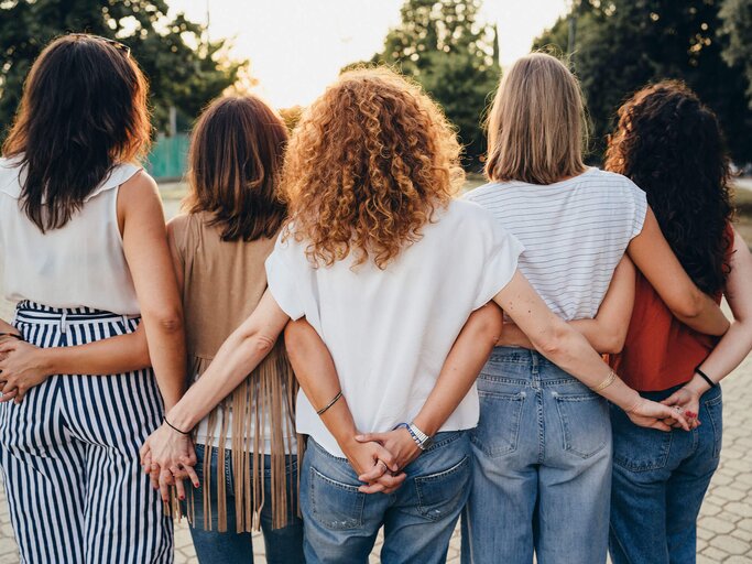 Gruppe von Freundinnen, die sich an den Händen halten, von hinten fotografiert | © iStock | FilippoBacci