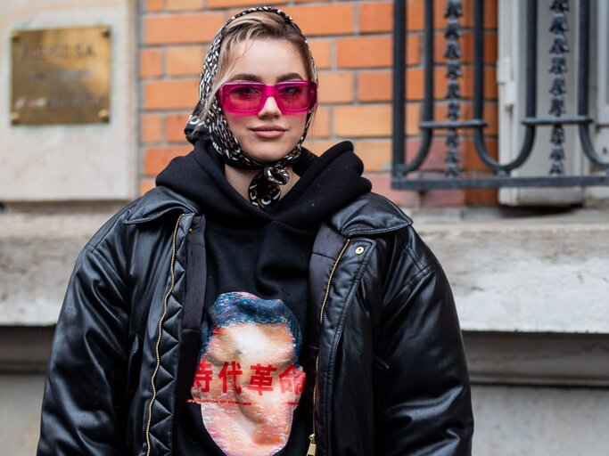 Junge Frau trägt eine Sonnenbrille mit transparentem Rahmen in der Trendfarbe Pink. | © Getty Images | Christian Vierig