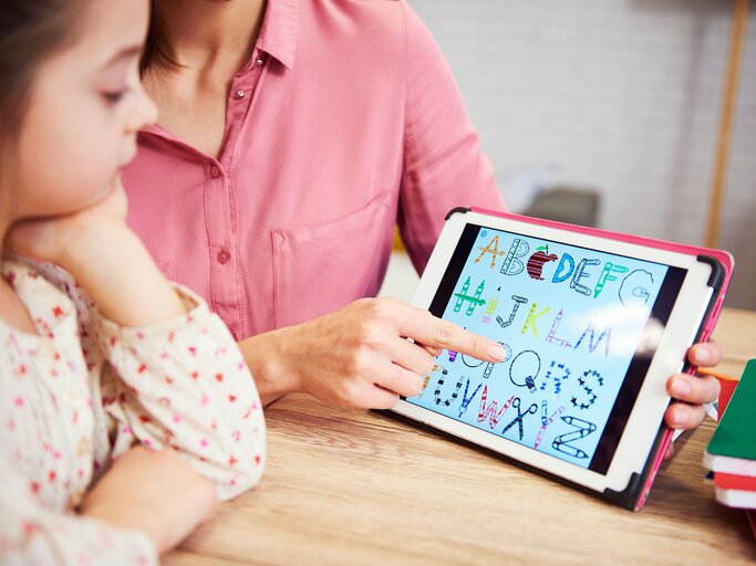 Mutter lernt mit dem Kind an einem Tablet | © iStock | gpointstudio