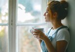 Frau sitzt auf der Fensterbank und denkt nach. | © iStock | Jasmina007