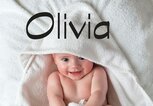 Baby liegt mit einem Handtuch eingewickelt im Bett - dazu der Babyname Olivia | © iStock | SolStock