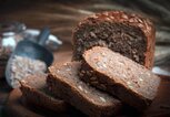 Aufgeschnittenes Vollkornbrot auf rustikalem Holzbrett. | © iStock.com / arfo