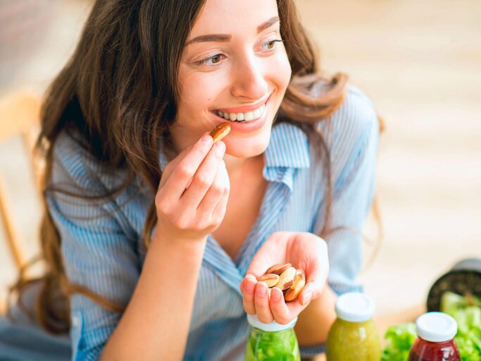 Eine Frau isst eine Paranuss. | © iStock.com / RossHelen