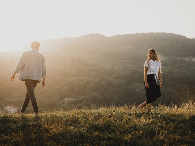 Frau und Mann stehen distanziert auf einer Wiese | © Getty Images/	Halfpoint Images