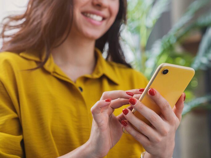 Frau ist glücklich und blickt auf ihr Smartphone | © gettyimages.de / Inside Creative House