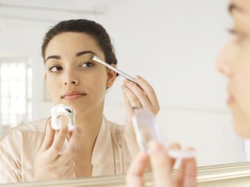 Frau schminkt sich vor einem Spiegel | © GettyImages/Christopher Robbins
