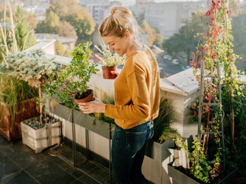 Frau kümmert sich um ihre Balkonpflanzen | © GettyImages/	AleksandarNakic