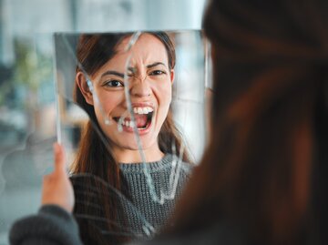 Frau blickt wütend in ihr Spiegelbild | © GettyImages/PeopleImages