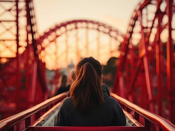 Frau sitzt in einem roten Achterbahnwagon | © Adobe Stock/Yuliia