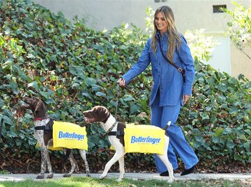 Heidi Klum in einem Denim-Look mit ihren zwei Hunden spazierend | © Getty Images / Michael Simon