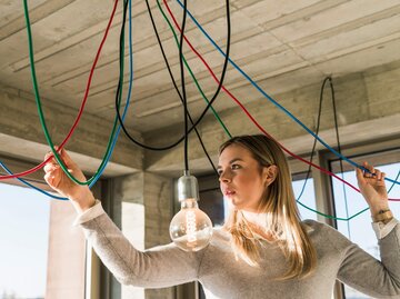 Frau arbeitet an Deckenlampe | © Getty Images/Westend61