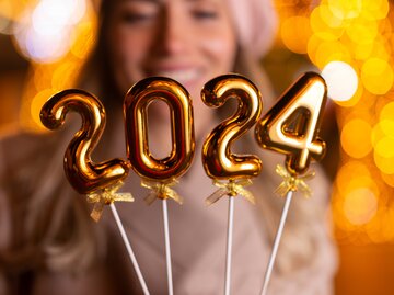 Frau hält Kerzen mit der Zahl 2024 | © AdobeStock/Dexon Dee