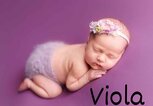 Ein Baby mit Blumenhaarband liegt schlafend auf einer Lila-Decke - unten Rechts im Bild der Mädchenname Viola. | © Adobe Stock/Svetlana