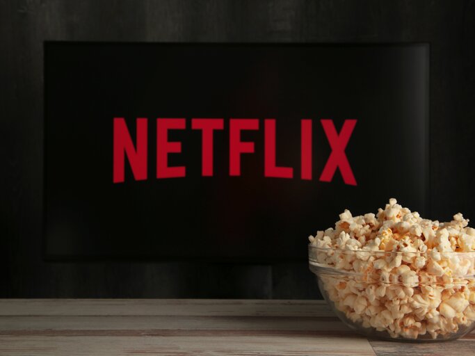 Netflix-Logo auf Fernseher mit Schüssel Popcorn davor | © AdobeStock/Mouse family